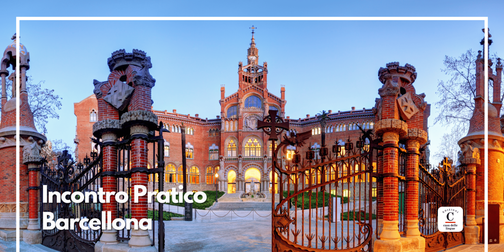 Un cancello decorato si apre su un imponente edificio in mattoni con torri e dettagli intricati al tramonto. La scritta "Incontro Pratico Barcellona" nell'angolo in basso a sinistra. Il cielo azzurro e gli alberi spogli incorniciano l'architettura storica.